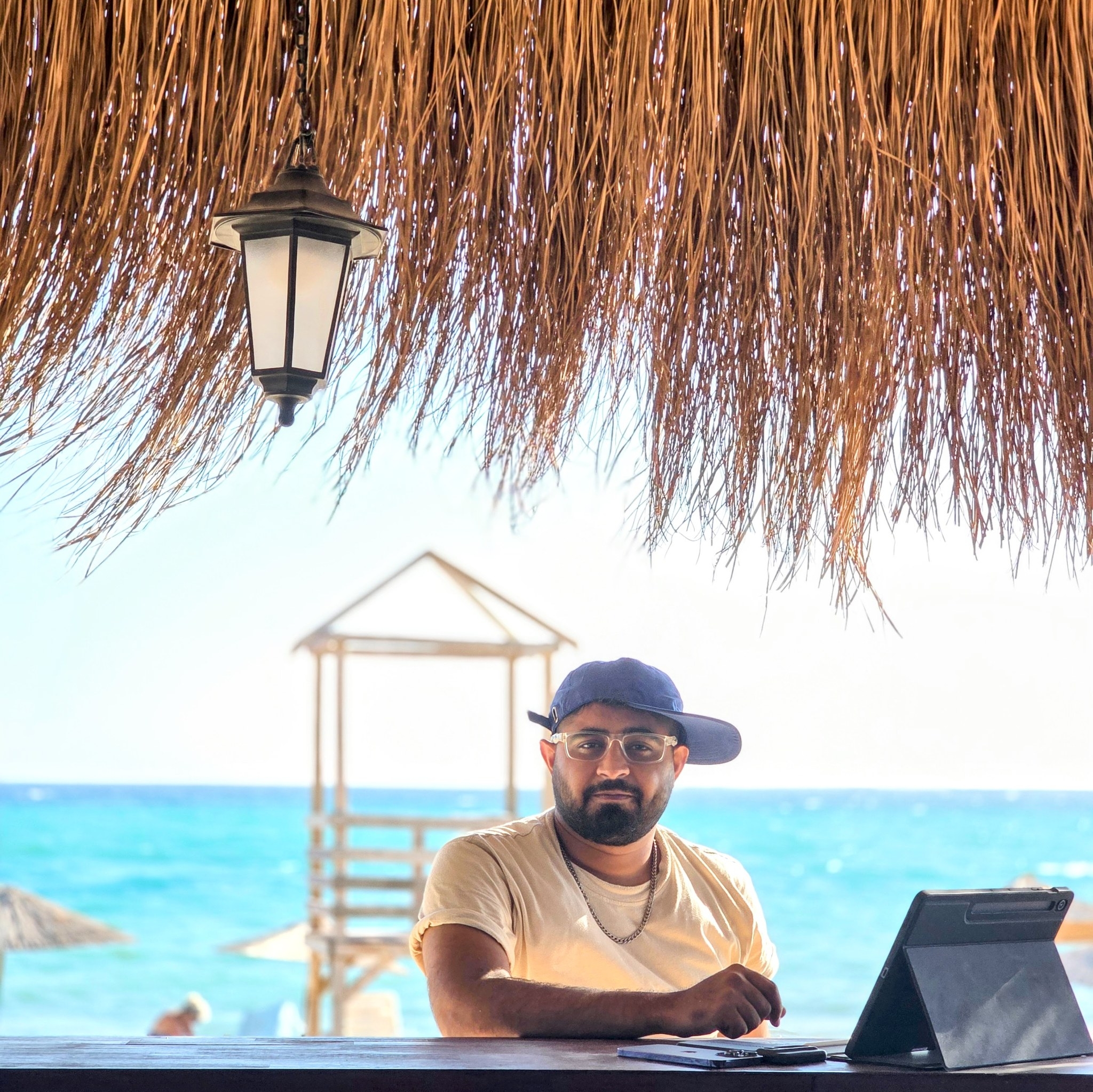 Najam Imran ek beach hut ke neeche baith kar apne tablet ke saath kaam kar rahe hain